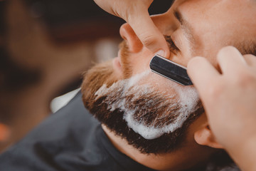 Man hipster having barber shave the barbershop.