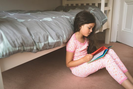 Girl reading book in bedroom