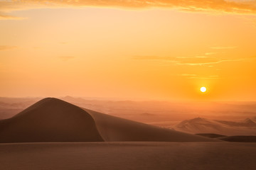 Fototapeta na wymiar Coucher de soleil et dunes de sable dans le désert de Huacachina au Pérou Aventure Excursion 