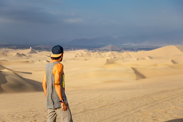Homme de dos regardant le désert et les dunes de sable à Hucachina au Pérou dans le désert