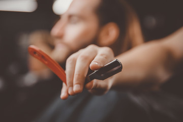 Obraz na płótnie Canvas Razor in foreground hands of barber. Concept barbershop for men.