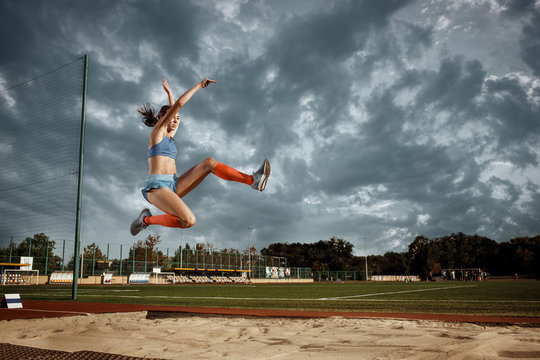 Female athlete performing a long jump during a competition at stadium. The jump, athlete, action, motion, sport, success, championship concept