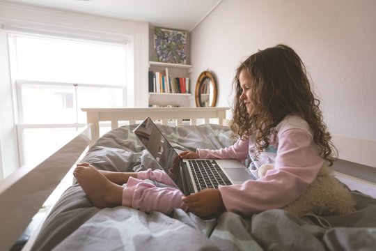 Girl using laptop on bed in bedroom