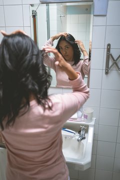 Woman standing with hand on hair in bathroom