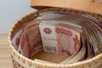 Big Russian money lies in a round wooden wicker box