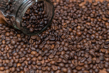 Coffee beans, poured from a glass transparent jar.
