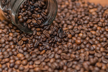 Coffee beans, poured from a glass transparent jar.