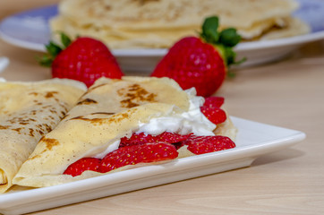 primer plano de unos crepes rellenos  con nata y fresas 