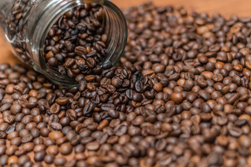 Coffee beans, poured from a glass transparent jar.