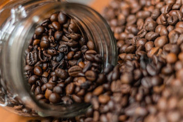 Coffee beans, poured from a glass transparent jar.