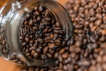 Coffee beans, poured from a glass transparent jar.