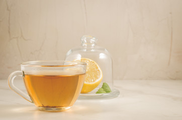 tea with a lemon and mint in glass cup/tea with a lemon and mint in glass cup on a white marble. Copy space
