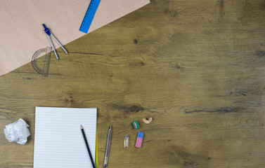 A photo of stationery set: pencil, rubber, sharpener, compass, protractor, ruler and crumpled paper...