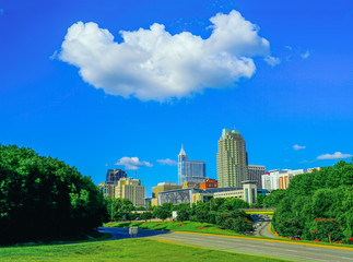 Obraz premium A skyline of Raleigh, North Carolina with a white puffy cloud lover the city.