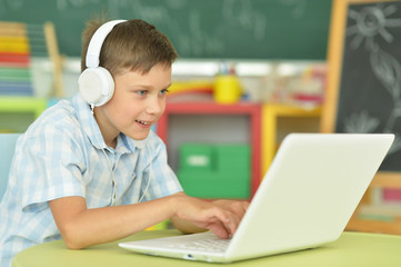 boy with headphones using laptop in classroom