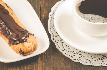 coffee cup and eclair/coffee cup and eclairs on a wooden background. Selective focus