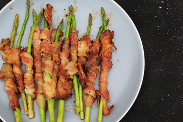 Top view of Grilled bacon wrapped green asparagus on dark background