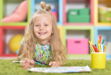 Portrait of cute little girl drawing on floor