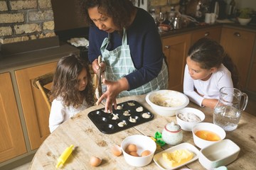 Grandmother with her granddaughters preparing breakfast on