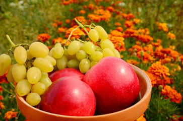 Red ripe apples with grapes in the plate.