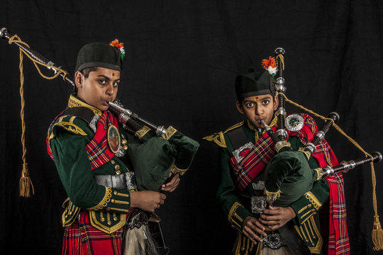 Two pipers of an Indian American Scottish bagpipe looking at camera in full Scottish regalia, including kilts and sporrans