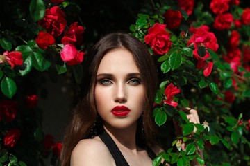 Portrait of  beautiful young woman in the rose garden, spring time, rose flowers blossoms.