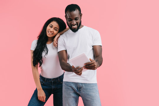 Young African American Couple Using Digital Tablet Isolated On Pink Background