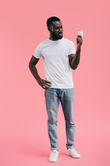 young african american man with condom isolated on pink background
