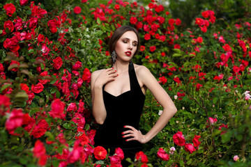 Portrait of beautiful young woman in the rose garden, spring time, rose flowers blossoms.