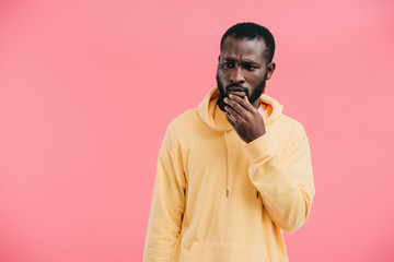 thoughtful young african american man with hand on chin isolated on pink background