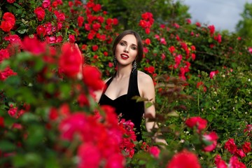 Portrait of beautiful young woman in the rose garden, spring time, rose flowers blossoms.