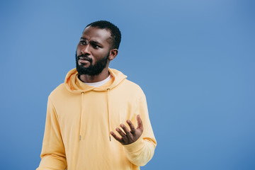 Fototapeta premium pensive young african american man gesturing by hand isolated on blue background