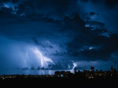 Fondo con cielo nocturno con nubes de tormenta, rayos y relampagos en tonos azulados.Noche de Tormenta con rayos sobre los edificios, en Valencia, Espa&ntilde;a.  10 de septiembre de 2018
