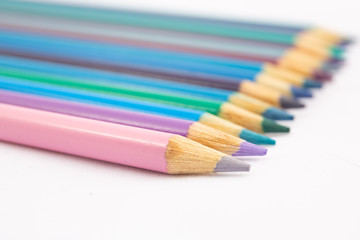 Colored pencils in cool shades at an angle on white background