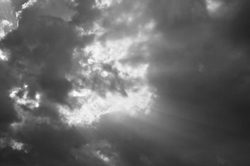 sunbeam spreading light through dark cloud on sky