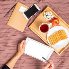 Woman lying on bed, drinking tea and looking at tablet, pay for purchases, online shopping. Mock up with white screen