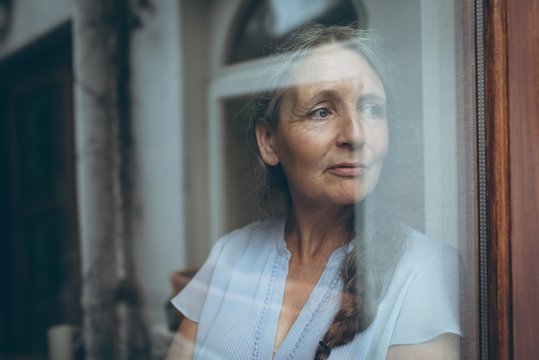 Senior woman looking through window at home