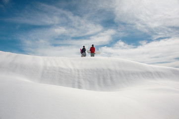 girl and guy in ski equipment with snowboards in hands stand on snow-covered road