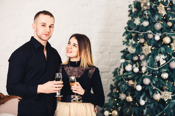 loving couple in stylish clothes with glasses of wine at Christmas.