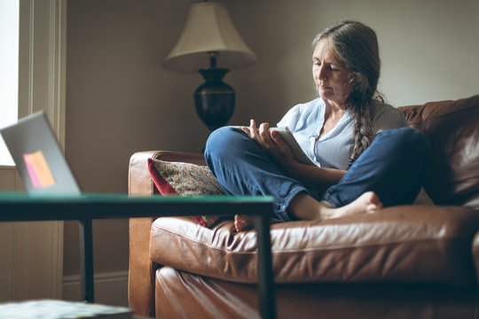 Senior woman writing on a notepad in living room