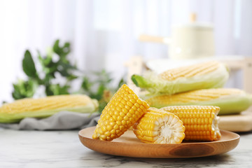 Plate with tasty sweet corn cob on table