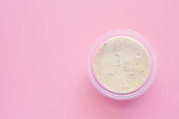 Homemade salad dressing in plastic bowl on pink background for food and eating concept