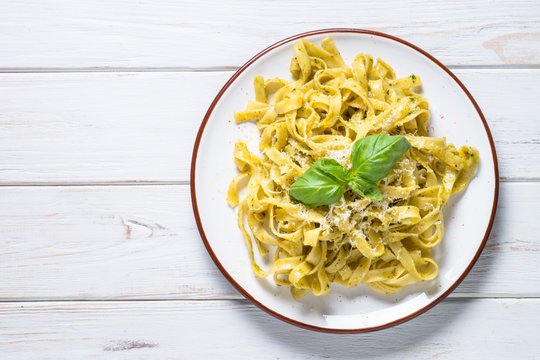 Tagliatelle pasta with pesto sauce and parmesan on white.
