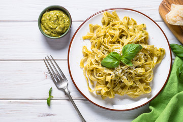 Tagliatelle pasta with pesto sauce and parmesan on white.
