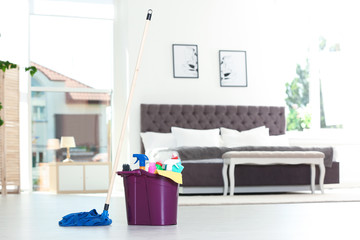 Bucket with cleaning supplies and mop on floor indoors