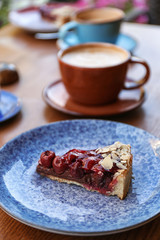 Plate with slice of cherry cake on wooden table
