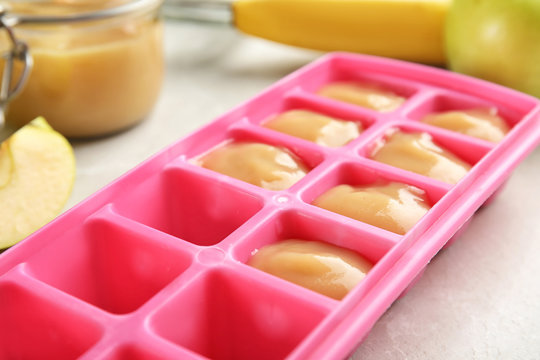 Ice cube tray with healthy baby food on table
