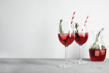 Glasses of fresh cranberry cocktail with rosemary and space for text on light background