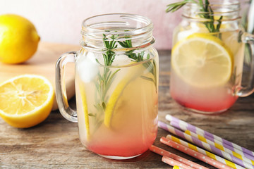 Refreshing lemon cocktail with rosemary in mason jars on table