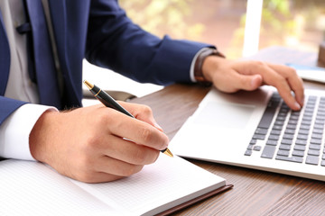 Lawyer working with laptop at table, focus on hands
